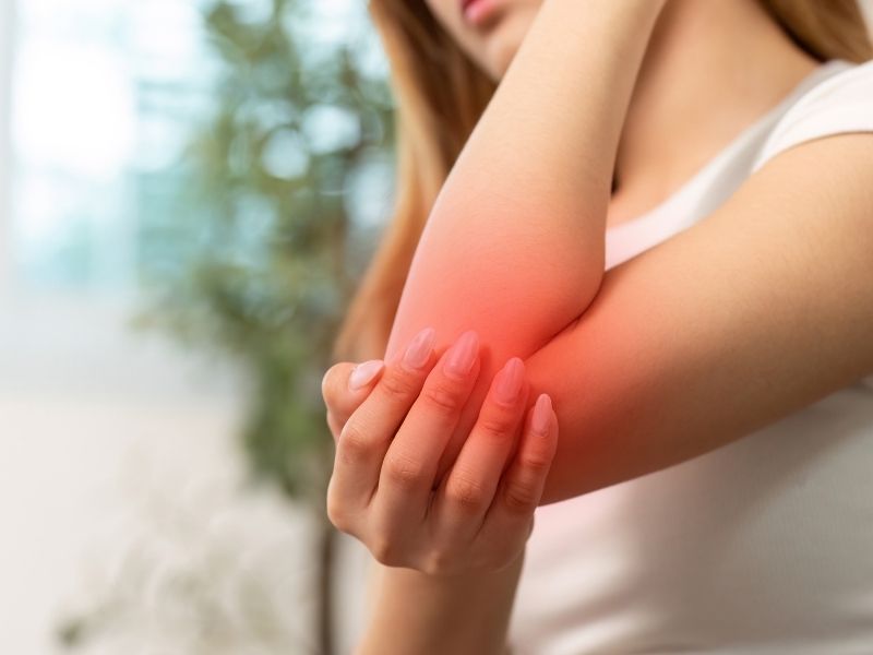 woman holding elbow in pain