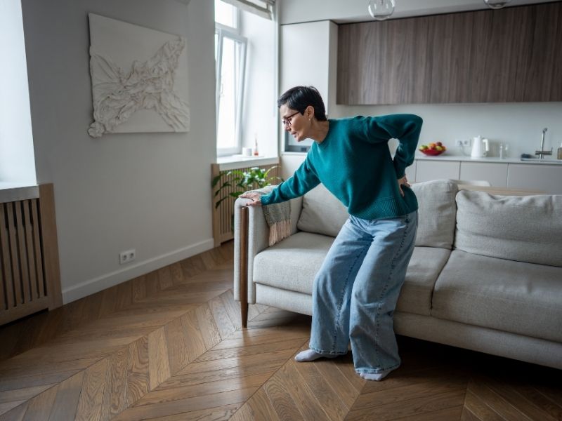 Elderly person in pain with hand on lower back