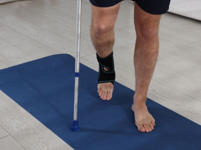 man walking with cane and a brace on his right foot